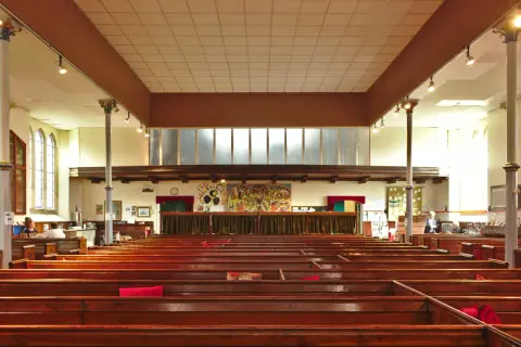 Intérieur d'une église protestante, avec des bancs en bois verni et une fresque colorée au mur. Un lieu paisible pour un baptême chez les protestants.