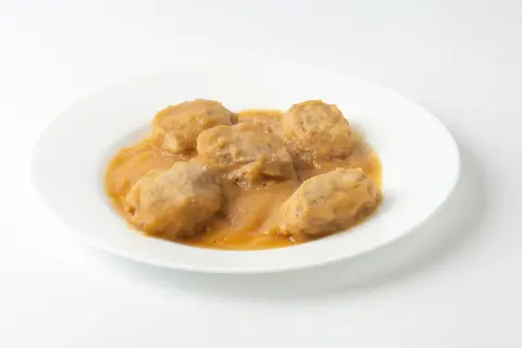 Solomillo de cerdo con manzana en salsa, servido en un plato blanco.