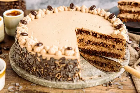 Eine köstliche Kaffee Torte mit Schokoladenraspeln und Kaffeebohnen-Dekoration. Ein Stück wurde bereits angeschnitten.