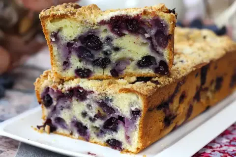 Ein saftiger Blaubeer Streuselkuchen, mit vielen Blaubeeren und knusprigen Streuseln, auf einem weißen Teller.