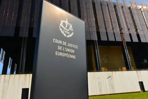 Tablica z napisem "Cour de Justice de l'Union Européenne" przed nowoczesnym budynkiem. To siedziba Trybunału Sprawiedliwości Unii Europejskiej.