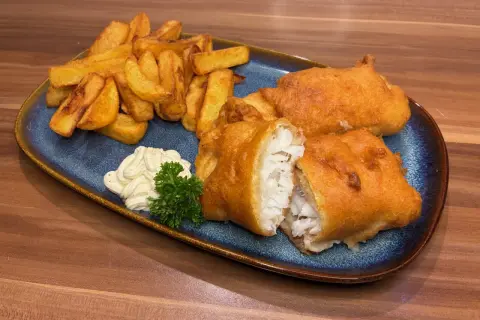 Knuspriges Fish and Chips Rezept: goldbraun frittierter Fisch mit Pommes, dazu Remoulade und Petersilie.