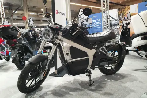 Czarny motocykl elektryczny Horwin CR6 na wystawie, obok innych pojazdów elektrycznych.