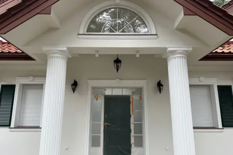 Elegancki pilaster zdobi fasadę domu, wspierając dach nad wejściem.