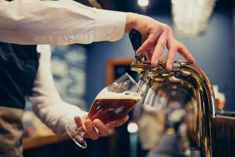 Barman nalewa piwo do kieliszka. Zastanawiasz się, ile piwa na wesele? Oto odpowiedź!