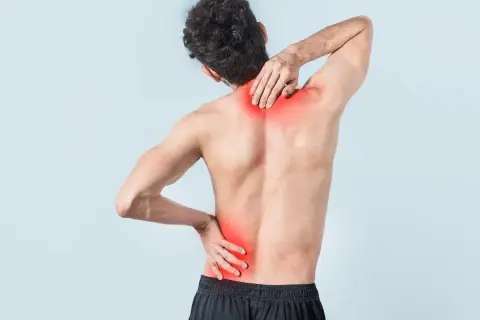 Uomo con dolore alla schiena bassa, evidenziato in rosso. Quanto dura uno strappo muscolare alla schiena bassa?