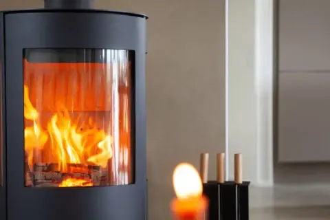 Moderner Kaminofen mit sichtbarem Feuer, erfüllt BIMSCHV Stufe 2. Gemütliches Ambiente im Wohnraum.
