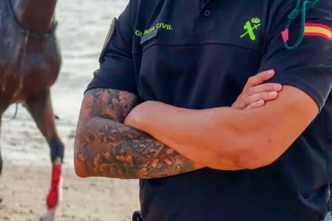 Agente de la Guardia Civil con tatuajes florales en el brazo, mostrando que los tatuajes en el trabajo son cada vez más aceptados.