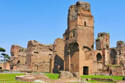 Imponenti rovine delle terme di Caracalla a Roma, con torri di mattoni che si ergono contro il cielo azzurro.