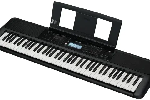 Czarny elektroniczny instrument klawiszowy Yamaha z nutami na stojaku. Idealny do nauki gry.