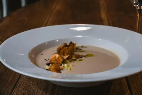 Krämig soppa med krispiga chips och olivolja, serverad på Radisson Blu Helsingborg restaurang.
