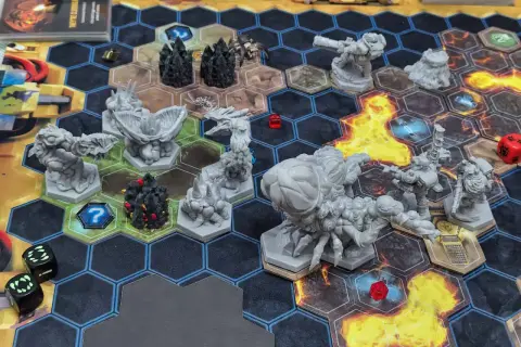 Das **Deep Rock Galactic Brettspiel** zeigt eine spannende Szene mit Zwergen-Miniaturen, Monstern und Würfeln auf einem hexagonalen Spielfeld.