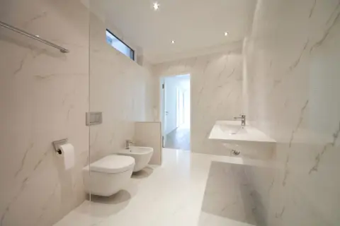 Bagno moderno con bidet e WC sospesi, lavabo a mensola e finiture in marmo. L'altezza scarico bidet è ottimale per un uso confortevole.