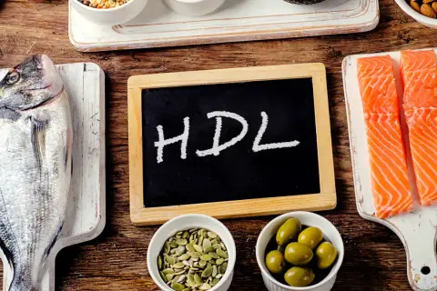 Ryba, łosoś, oliwki, pestki i tabliczka z napisem HDL na drewnianym tle.