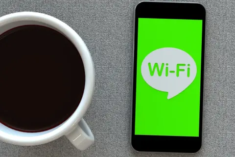 Kawa i smartfon z ikoną Wi-Fi. Zastanawiasz się, jak przyspieszyć internet?
