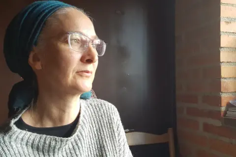 Anna Nachman, med glasögon och en turkos scarf, blickar utåt.