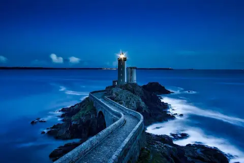 Un phare solitaire, tel un gardien des mers, éclaire la nuit. Son faisceau puissant guide les navires, rappelant les vers de Baudelaire sur la beauté sombre de l'océan.