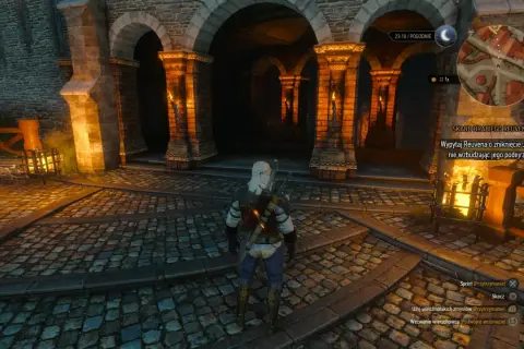 Geralt stoi przed arkadami, szukając skarbu hrabiego Reuvena. W tle widać pochodnie i kamienne mury.