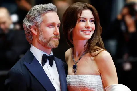 Anne Hathaway z mężem Adamem Shulmanem na czerwonym dywanie. Ona w olśniewającej sukni i biżuterii, on w eleganckim smokingu.