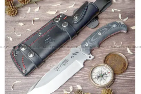Cuchillo Cudeman Entresierras con funda de cuero, brújula y detalles de naturaleza. Ideal para aventuras.