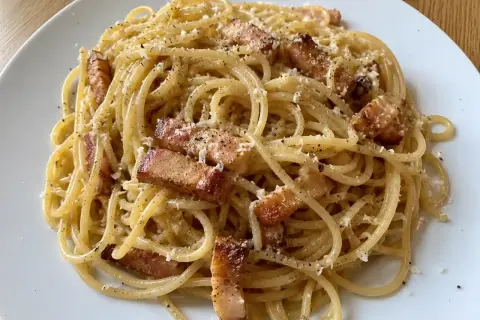 En portion riktig carbonara med spaghetti, knaprigt sidfläsk och rikligt med parmesanost.