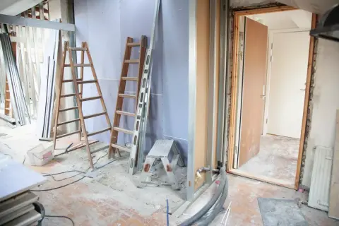 Remont wnętrza z drabinami, materiałami budowlanymi i otwartymi drzwiami. Sprawdzanie dopuszczalnej wilgotności ścian norma.