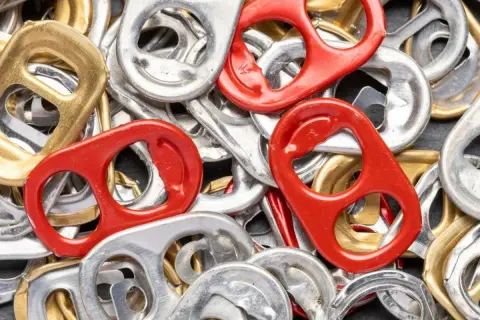 Mnóstwo srebrnych, złotych i czerwonych zawleczek od puszek tworzy barwną mozaikę. Co oznaczają zawleczki od puszek? To symbol recyklingu i możliwości tworzenia z nich czegoś nowego.