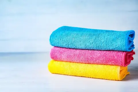 Tres paños apilados de tejido microfibra: azul, rosa y amarillo.