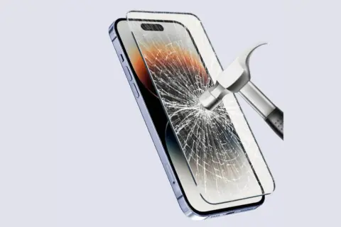 Młotek uderza w ekran telefonu, który jest chroniony przez szkło hybrydowe lub folię hydrożelową.