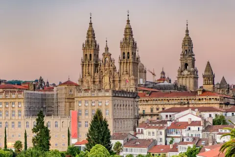 Majestatyczna katedra w Santiago de Compostela góruje nad miastem. W tle widać budynki i palmy.