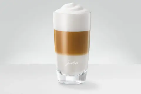 En hög latte macchiato med lager av mjölk och kaffe, toppad med ett fluffigt skum.