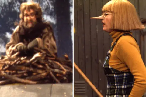 En man med skägg och glasögon sitter på en hög med ved. Bredvid honom en kvinna med näsa som Pinocchio, kanske är det ugglan Helge som har en hemlighet.