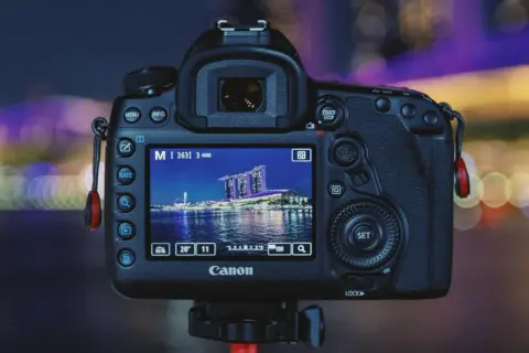 Aparat Canon z ekranem pokazującym nocną panoramę miasta. Dowiedz się, jak robić zdjęcia w ciemnych pomieszczeniach bez lampy, wykorzystując ustawienia aparatu.