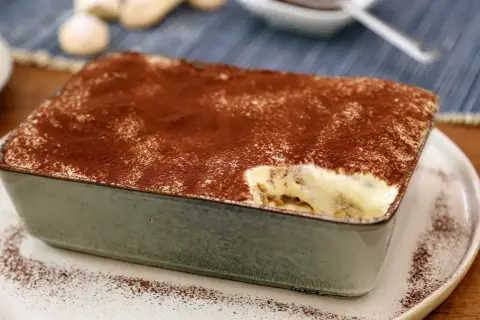 Un délicieux tiramisu pour 4 personnes, saupoudré de cacao, prêt à être dégusté.