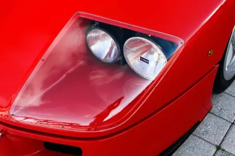 Der rote Ferrari f40 lm mit seinen charakteristischen Scheinwerfern unter einer transparenten Abdeckung.