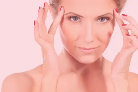 Mujer con manos en la frente, piel radiante tras carboxiterapia facial.