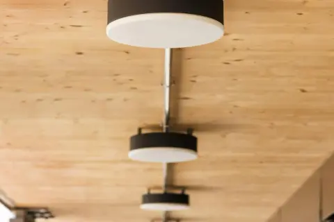 Nowoczesne lampy, każdy plafon ścienny z czarną obudową i białym dyfuzorem, zamontowane na drewnianym suficie.