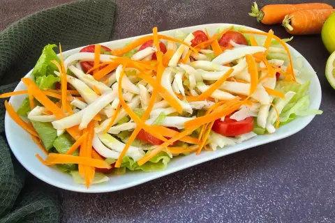 Deliziosa insalata di seppie con lattuga croccante, carote julienne e pomodorini freschi. Un piatto leggero e saporito.