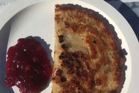 En gyllene kolbulle med lingonsylt på en vit tallrik. Perfekt för ett enkelt kolbulle recept.