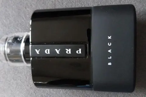 Elegancka, czarna butelka perfum Prada Black z białym logo.