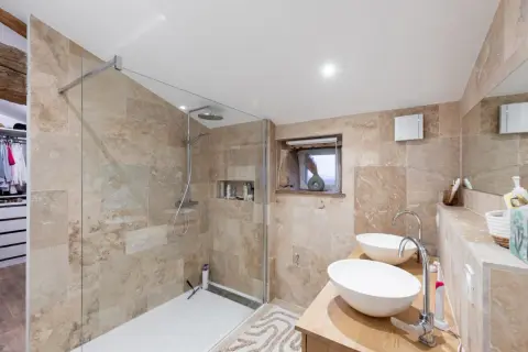 Salle de bain moderne avec douche vitrée, double vasque et dressing. Une rénovation qui pourrait permettre de déduire des impôts des travaux de salle de bain.