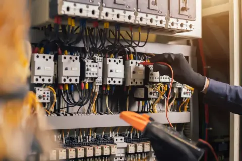 Main électrique d'une maison neuve, un technicien vérifie les connexions. Un devis électricité est essentiel pour ce type d'installation.