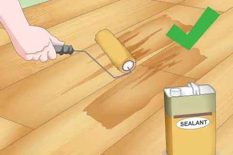 Application d'un scellant sur un plancher en bois. Le rouleau laisse une trace humide, signe que le produit pénètre bien le bois, éliminant toute rayure.