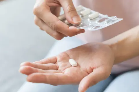 Dłoń z tabletką, która może być suplementem chrom na odchudzanie.