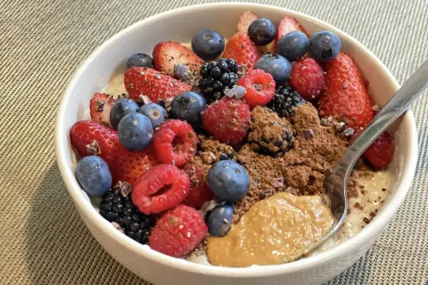 Schüssel mit overnight oats mit proteinpulver, Beeren, Kakao und Erdnussbutter.