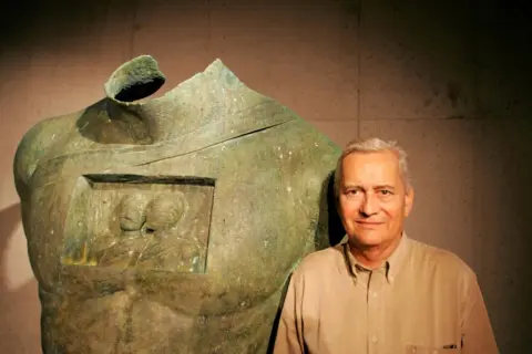 Igor Mitoraj obok swoich monumentalnych dzieł, rzeźby z brązu z wyobrażeniem dwóch postaci.