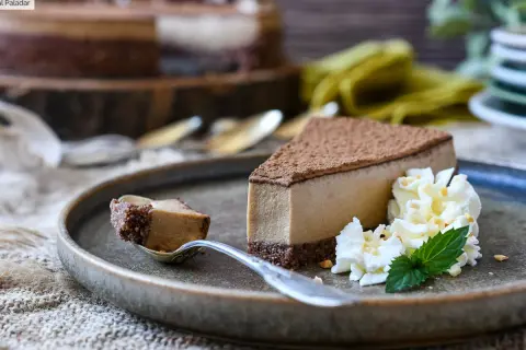 Deliciosa tarta de café con queso Philadelphia, cubierta de cacao y acompañada de nata montada y menta.