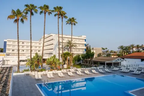 Basen i leżaki przy hotelu TUI Suneo Santa Ponsa. Palmy i biały budynek hotelowy na tle błękitnego nieba.