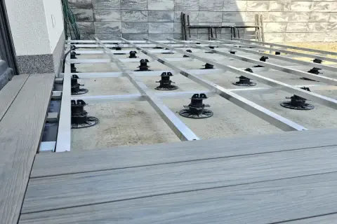 Budowa tarasu z deski kompozytowej. Widoczna konstrukcja nośna z aluminiowych profili na regulowanych podporach.