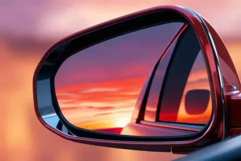 El retrovisor lateral, que es obligatorio, refleja un atardecer vibrante.